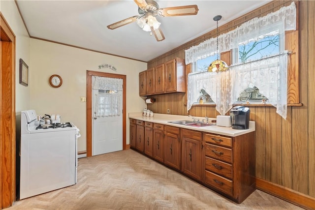 kitchen with white range, sink, pendant lighting, light parquet flooring, and washer / clothes dryer