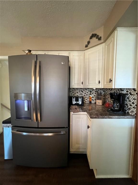 kitchen featuring backsplash, dark wood-type flooring, white cabinets, stainless steel fridge, and a textured ceiling