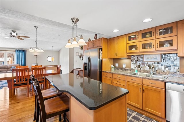 kitchen with a center island, sink, light hardwood / wood-style flooring, ceiling fan, and stainless steel appliances