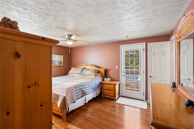 bedroom featuring hardwood / wood-style floors, a textured ceiling, access to outside, and ceiling fan