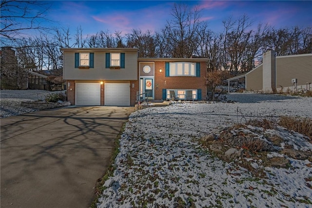 view of front facade featuring driveway, brick siding, and an attached garage