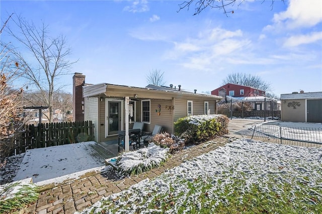 snow covered rear of property with a patio area and a storage shed