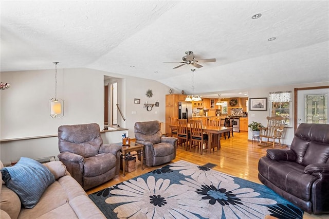 living room with a textured ceiling, light hardwood / wood-style floors, vaulted ceiling, and ceiling fan