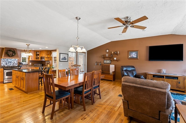 dining space featuring a textured ceiling, light hardwood / wood-style floors, ceiling fan, and lofted ceiling