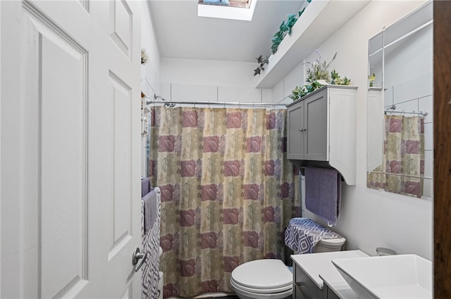 bathroom featuring vanity, a skylight, toilet, and curtained shower