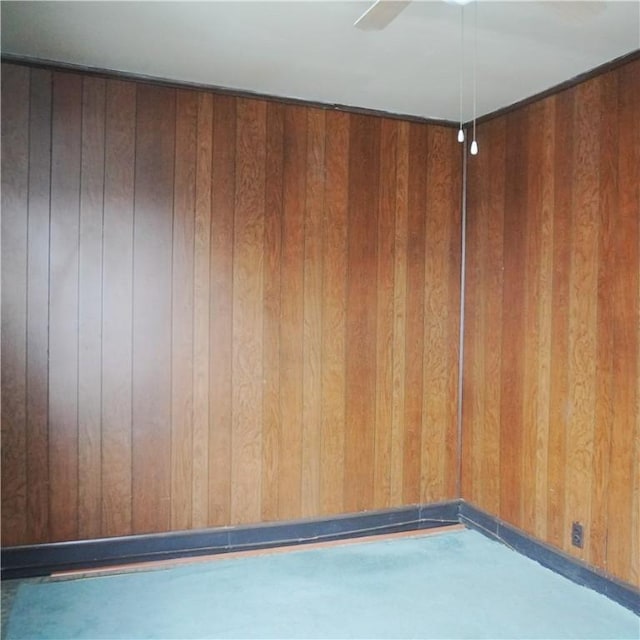 spare room with ceiling fan and wood walls