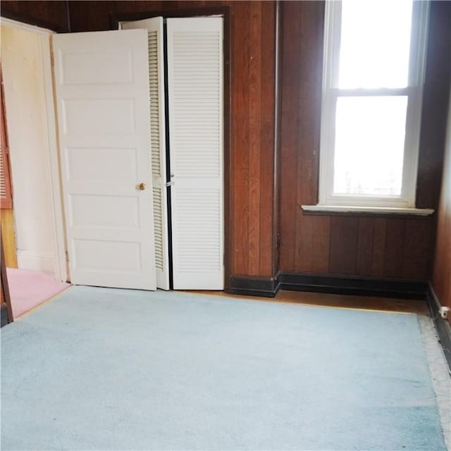 unfurnished bedroom featuring carpet floors and wooden walls