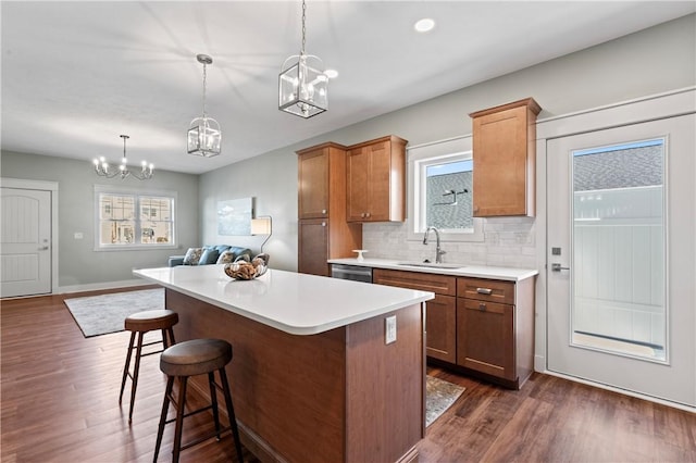 kitchen with backsplash, dark wood-type flooring, sink, pendant lighting, and a kitchen island