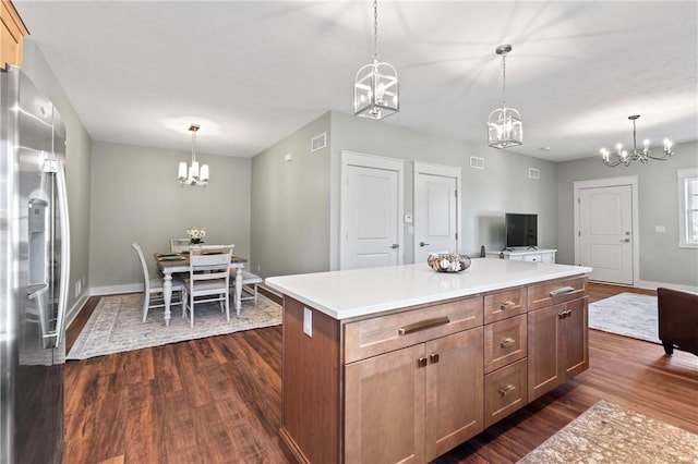 kitchen with decorative light fixtures, stainless steel fridge, a kitchen island, and dark hardwood / wood-style floors