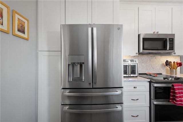 kitchen with light stone counters, white cabinetry, backsplash, and appliances with stainless steel finishes