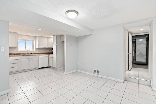 kitchen featuring white cabinets, light tile patterned floors, sink, and a textured ceiling