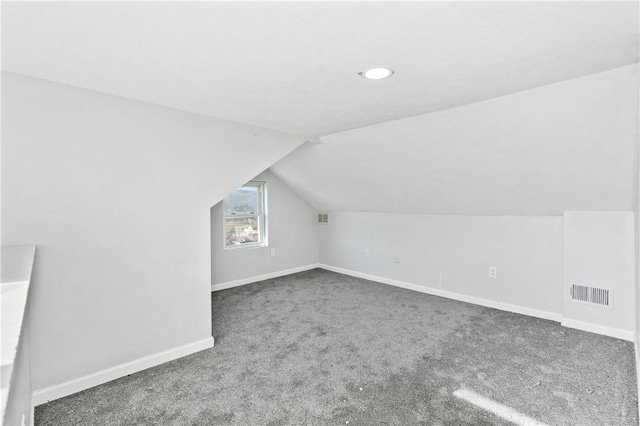 additional living space with dark colored carpet and lofted ceiling