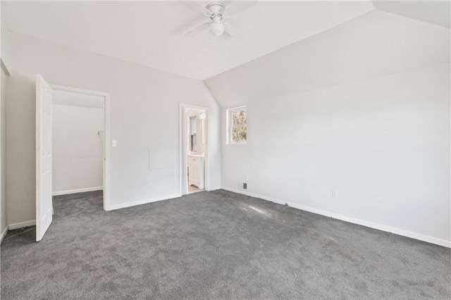 unfurnished bedroom with ensuite bath, ceiling fan, dark carpet, and vaulted ceiling