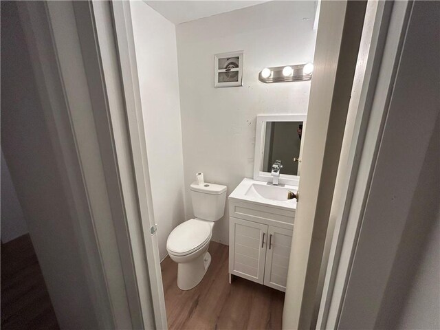 bathroom with toilet, vanity, and hardwood / wood-style flooring