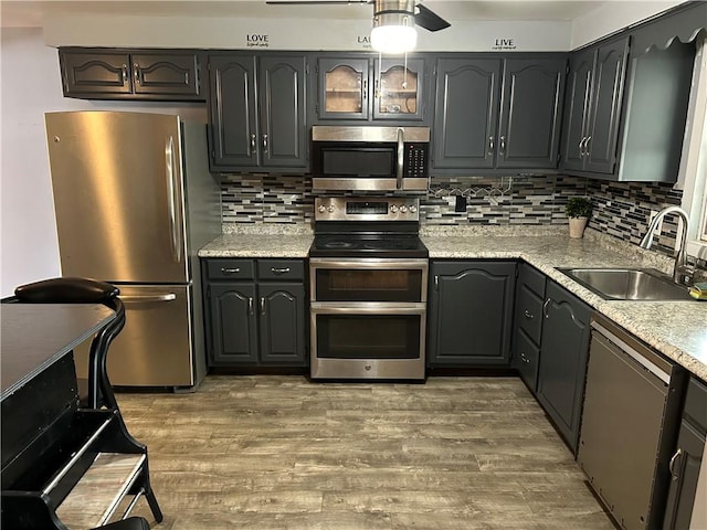 kitchen with light stone countertops, stainless steel appliances, decorative backsplash, sink, and dark hardwood / wood-style floors