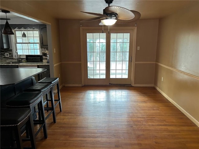 dining room featuring ceiling fan, wood-type flooring, sink, and a baseboard heating unit