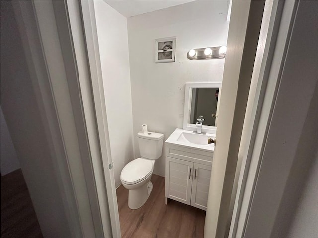 bathroom with toilet, vanity, and hardwood / wood-style flooring