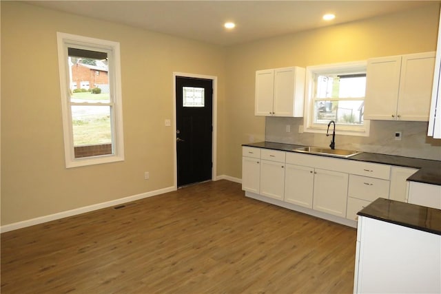 kitchen featuring white cabinets, decorative backsplash, sink, and hardwood / wood-style flooring