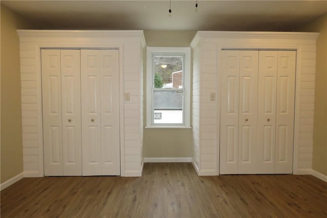 unfurnished bedroom with hardwood / wood-style floors and multiple closets