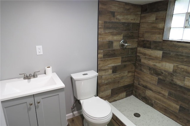 bathroom featuring tiled shower, vanity, hardwood / wood-style flooring, and toilet