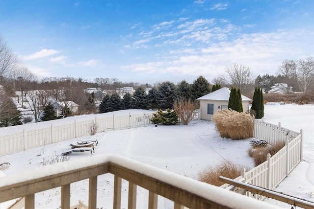 snowy yard featuring a detached garage and a fenced backyard