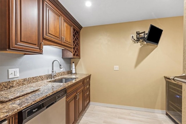 kitchen with stone countertops, light wood-style flooring, a sink, baseboards, and dishwasher