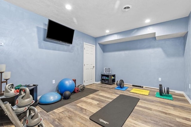 exercise area with baseboards, visible vents, wood finished floors, and recessed lighting