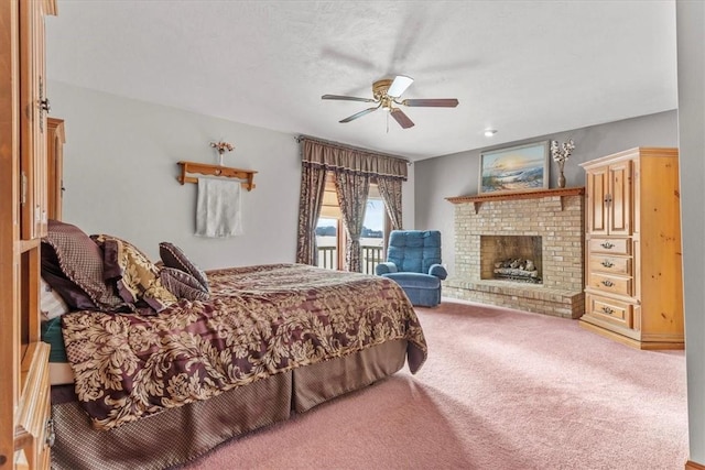 carpeted bedroom with access to exterior, a fireplace, and a ceiling fan