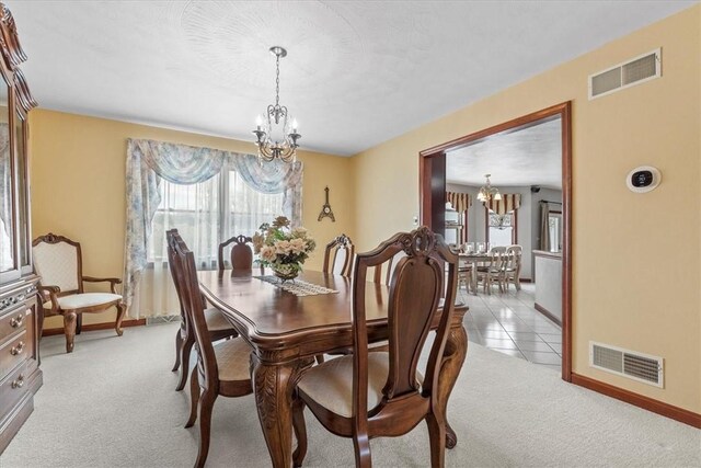 dining area with an inviting chandelier, baseboards, visible vents, and light colored carpet