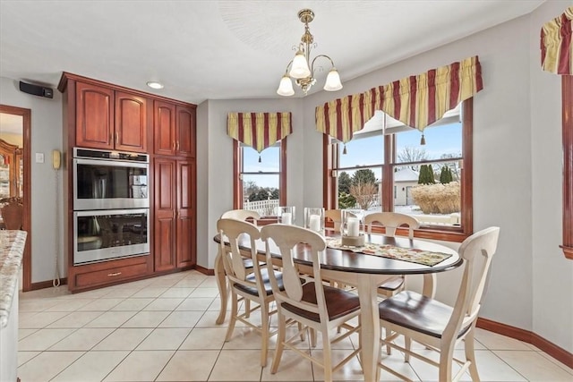 dining space with light tile patterned floors, baseboards, and a notable chandelier