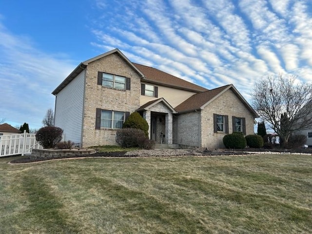 traditional home featuring a front yard, brick siding, and fence