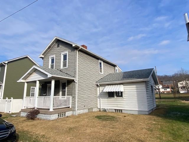 rear view of property with covered porch and a yard