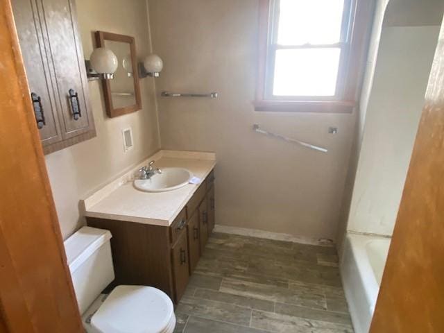 bathroom with vanity, a bath, and toilet