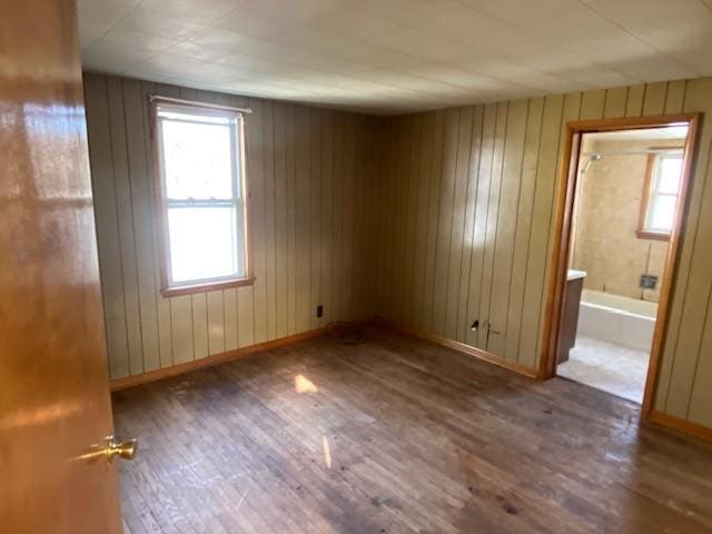 empty room with hardwood / wood-style flooring and wooden walls