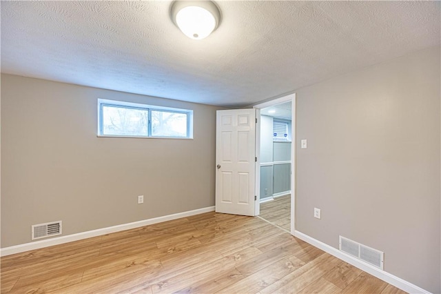 empty room with a textured ceiling and light wood-type flooring