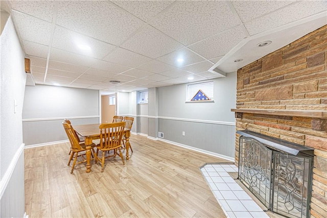 dining area featuring hardwood / wood-style floors, a paneled ceiling, and a fireplace