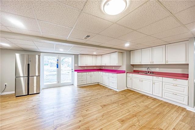 kitchen with stainless steel refrigerator, light hardwood / wood-style flooring, white cabinets, and sink