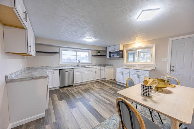 kitchen featuring appliances with stainless steel finishes, dark hardwood / wood-style flooring, a textured ceiling, sink, and white cabinets