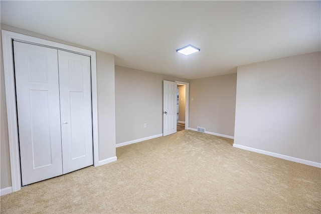 unfurnished bedroom featuring light colored carpet and a closet