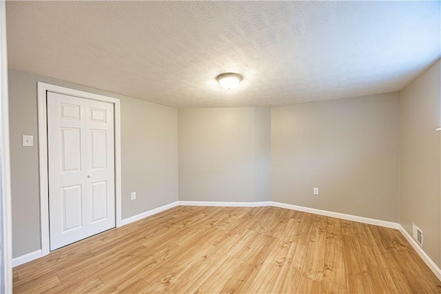 unfurnished bedroom with a textured ceiling, light hardwood / wood-style flooring, and a closet