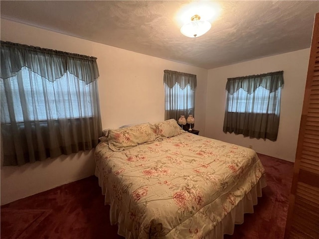 bedroom with a textured ceiling and dark colored carpet