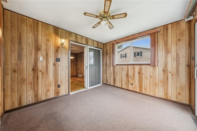 empty room with carpet flooring, wooden walls, and ceiling fan