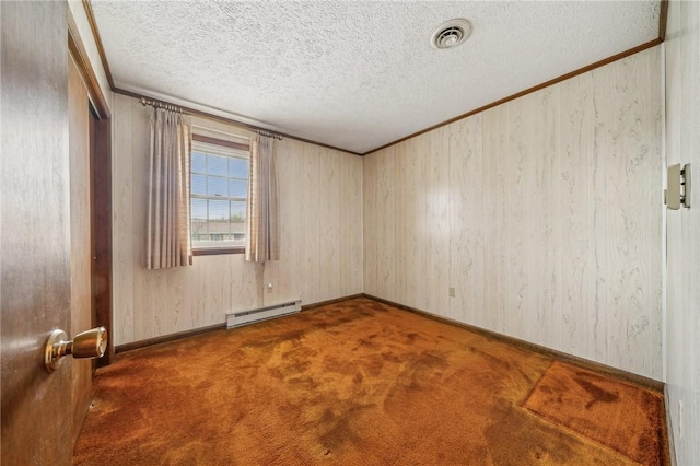 carpeted spare room featuring wood walls, a textured ceiling, and a baseboard heating unit