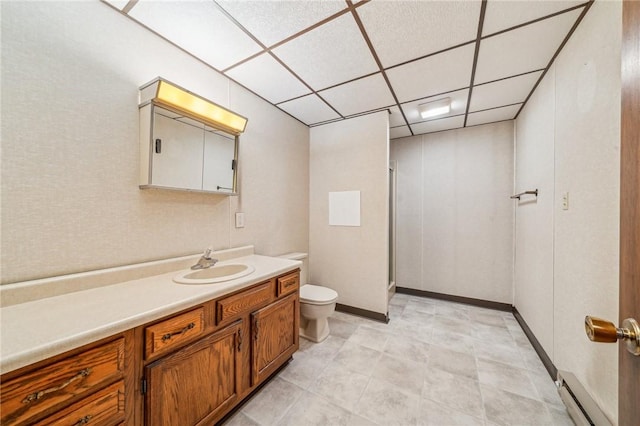 bathroom featuring a paneled ceiling, vanity, toilet, and a baseboard heating unit