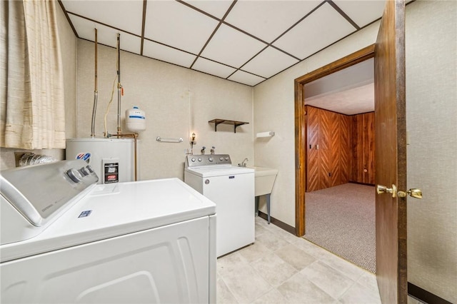 washroom with separate washer and dryer, water heater, and light carpet