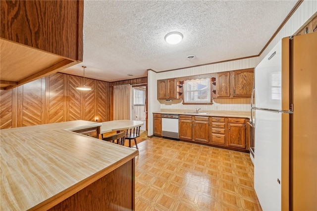 kitchen with kitchen peninsula, a textured ceiling, white appliances, crown molding, and decorative light fixtures