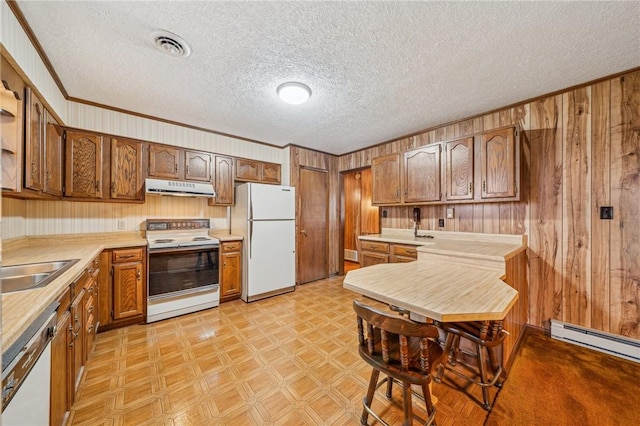 kitchen with white appliances, a textured ceiling, and wooden walls