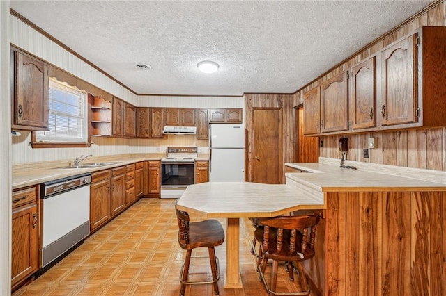 kitchen featuring sink, ventilation hood, kitchen peninsula, white appliances, and ornamental molding