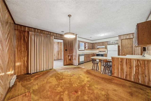 kitchen with a textured ceiling, kitchen peninsula, wood walls, and white appliances