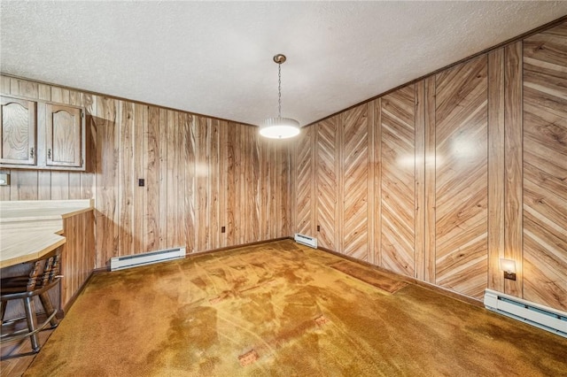 unfurnished dining area featuring a textured ceiling, wooden walls, and a baseboard heating unit